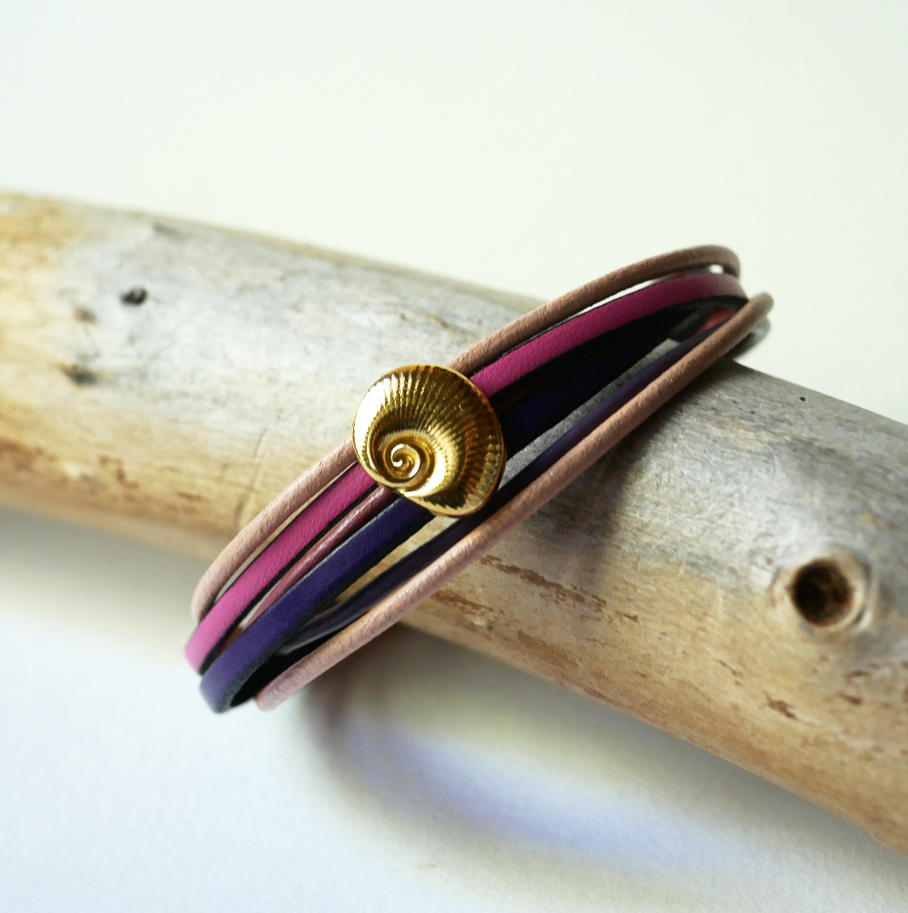 Bracciale a pi&ugrave; maglie in pelle color pesca e malva con decorazione a conchiglia dorata