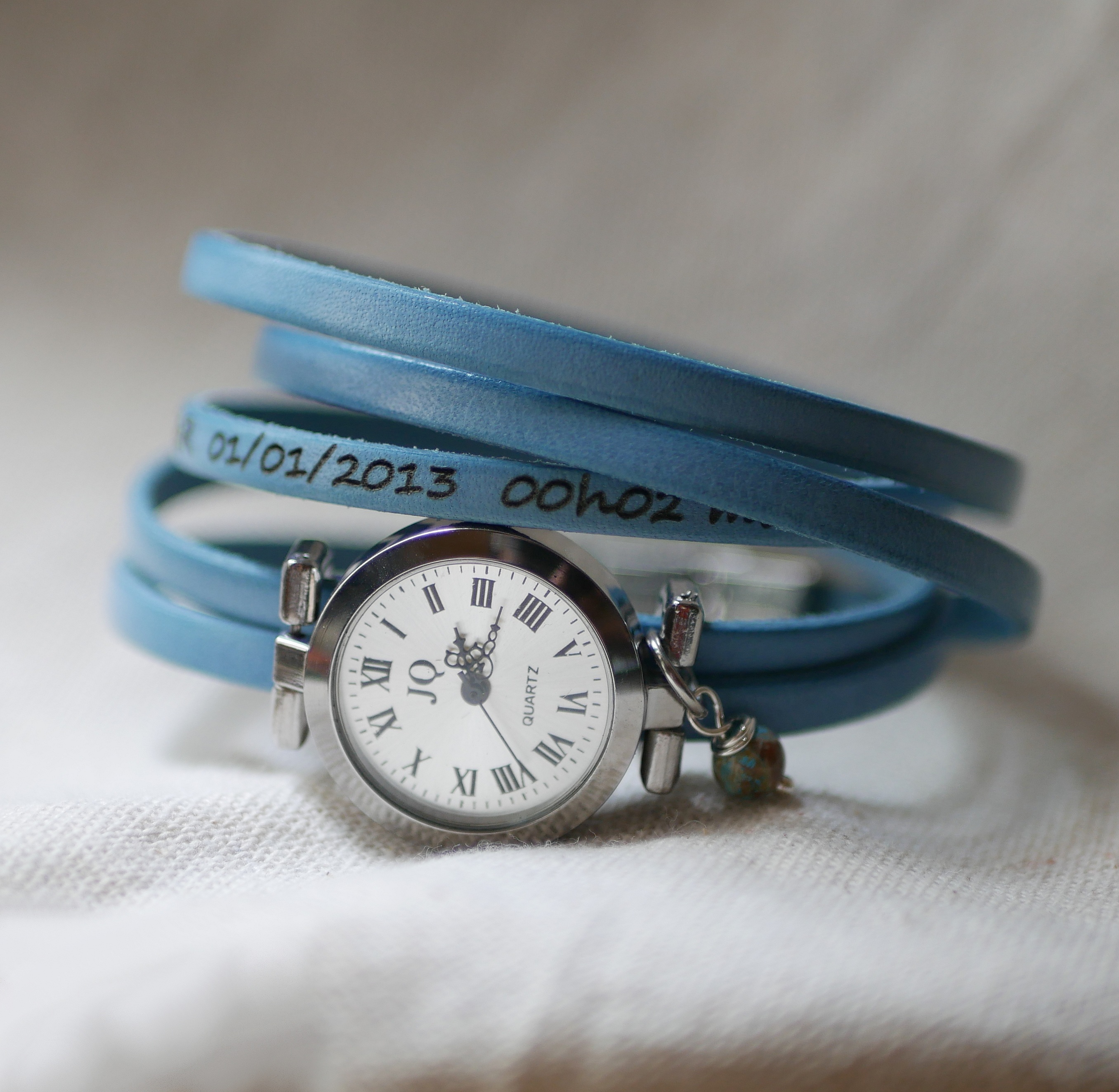 Montre argentée avec bracelet multi tours en cuir bleu.