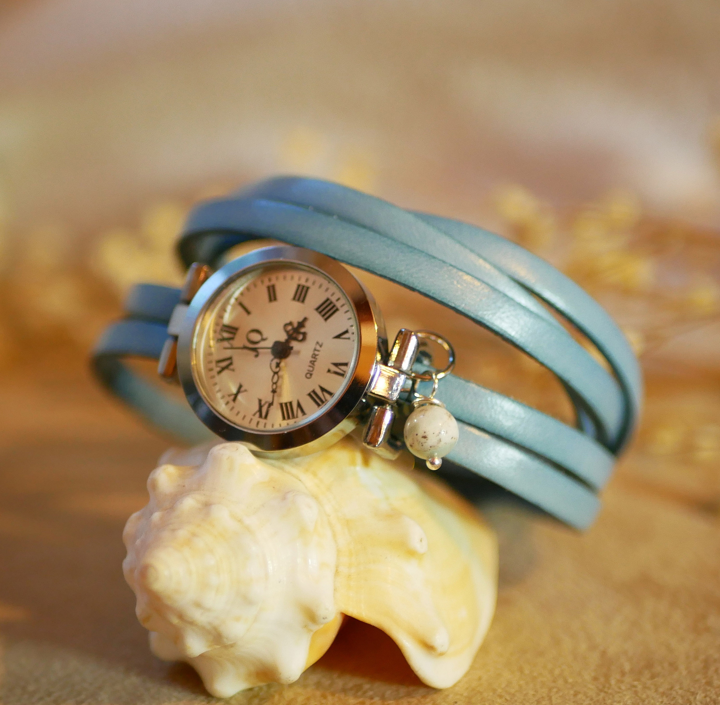 Montre argentée avec bracelet multi tours en cuir bleu.