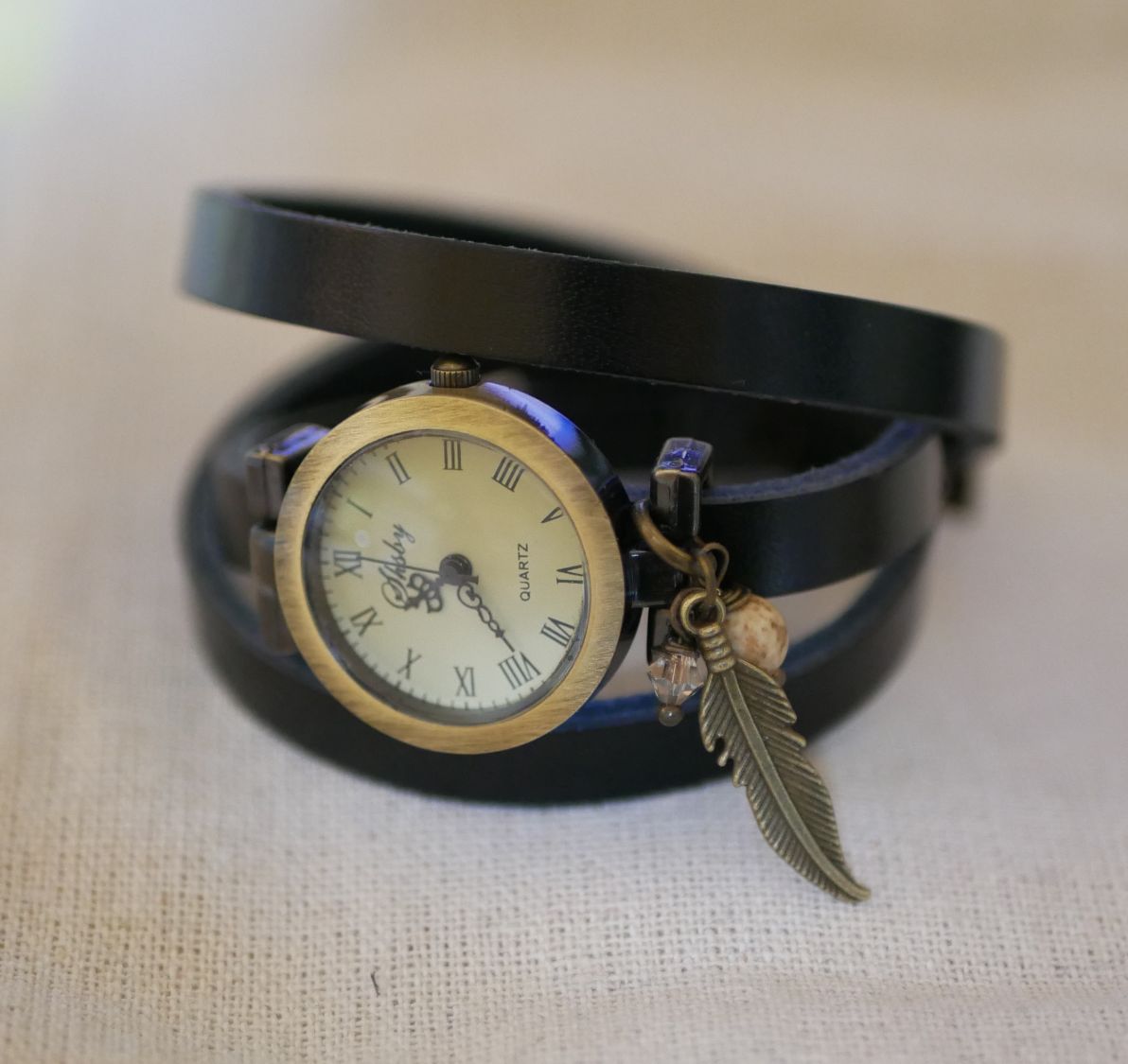 Orologio con bracciale in pelle e ciondoli con piume e perle